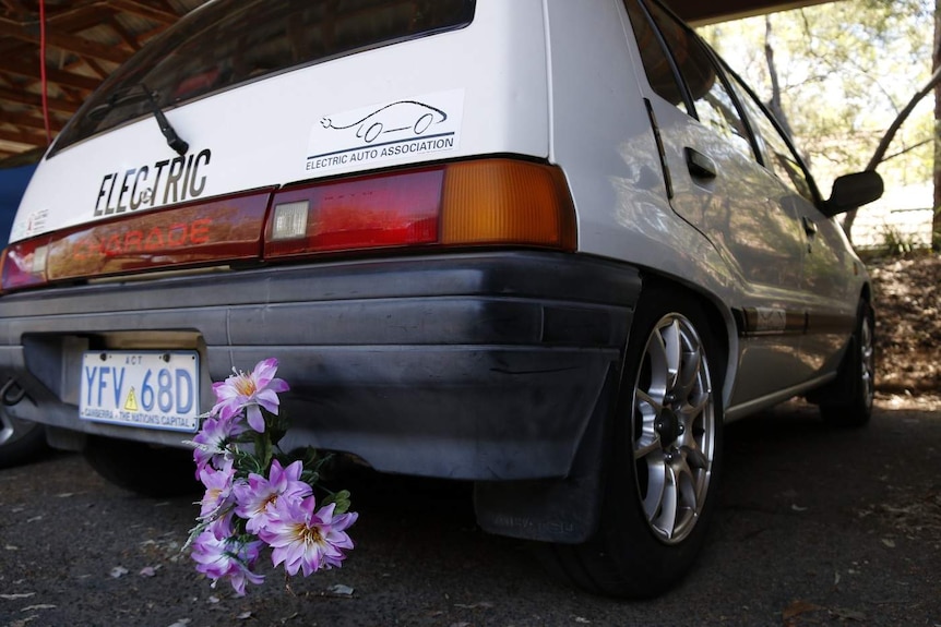 A small hatchback with flowers where the exhaust pipe should be.