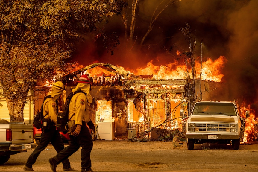 Firefighters pass a burning home