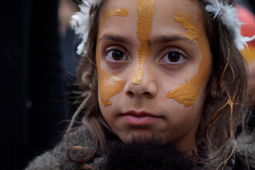 Close up of young girl with face painted in traditional ochre
