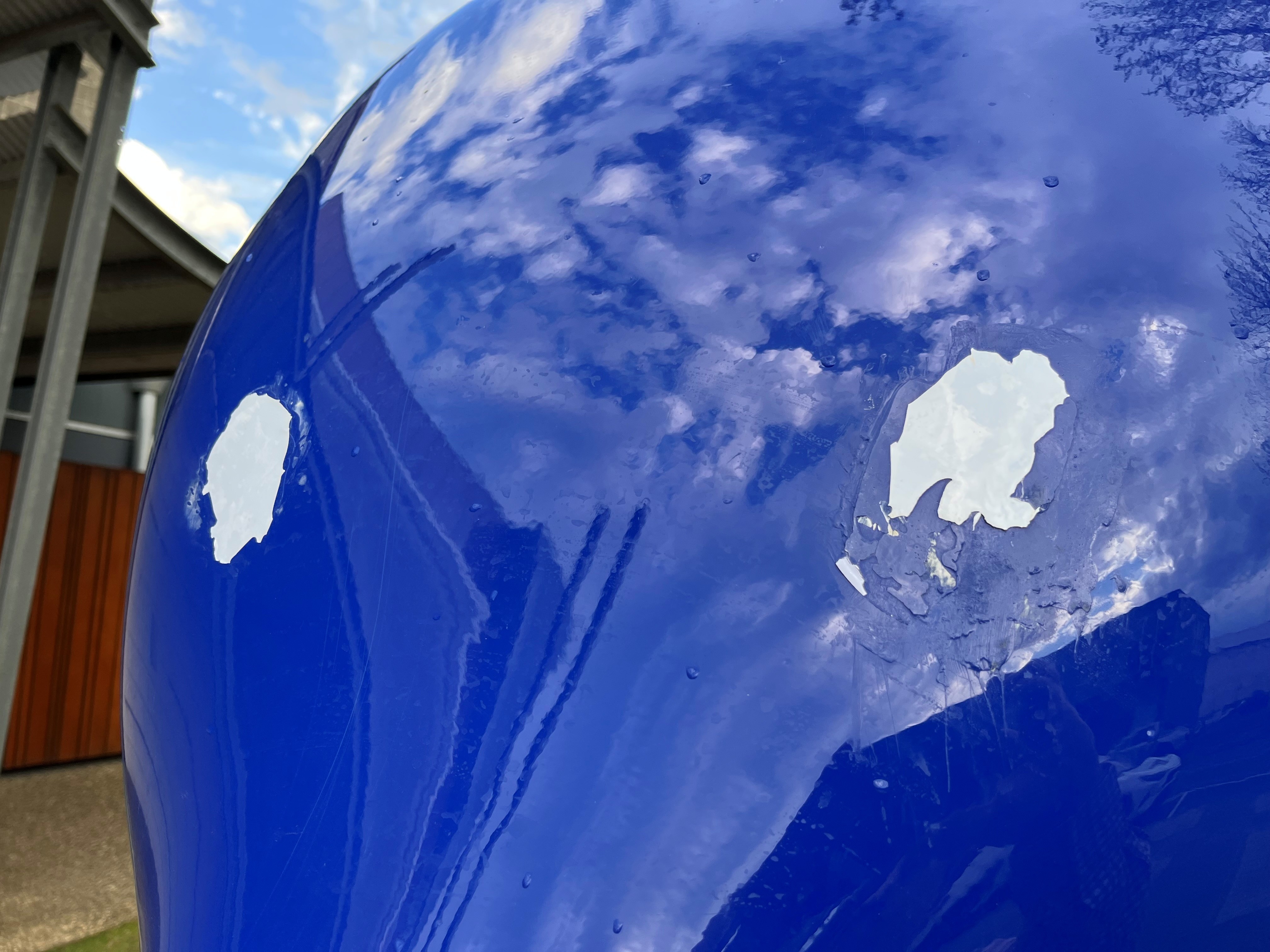 Large white marks in the shape of eyes on a large blue sculpture.