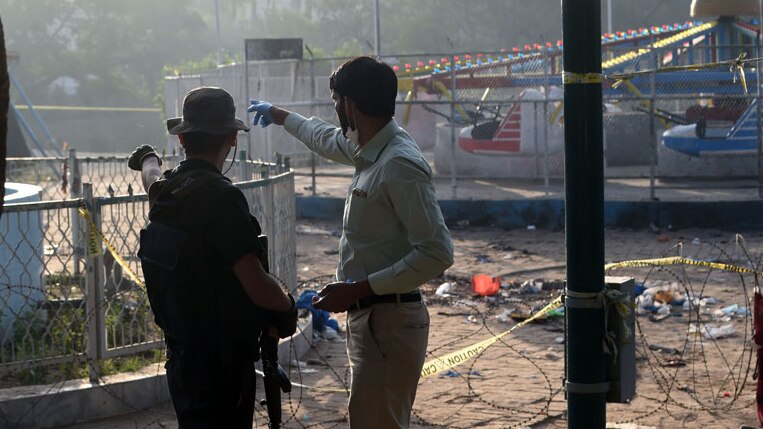 Pakistani security officials examine the cordoned-off site of the March 27 suicide bombing, in Lahore.