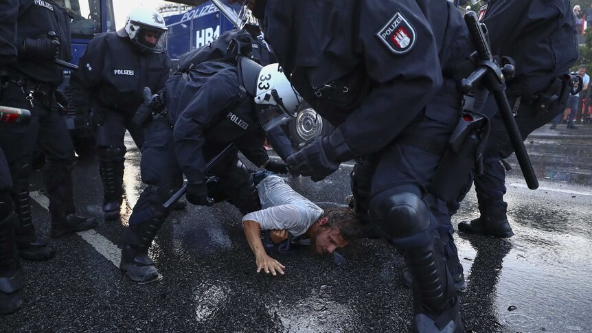 German riot police detain a man.