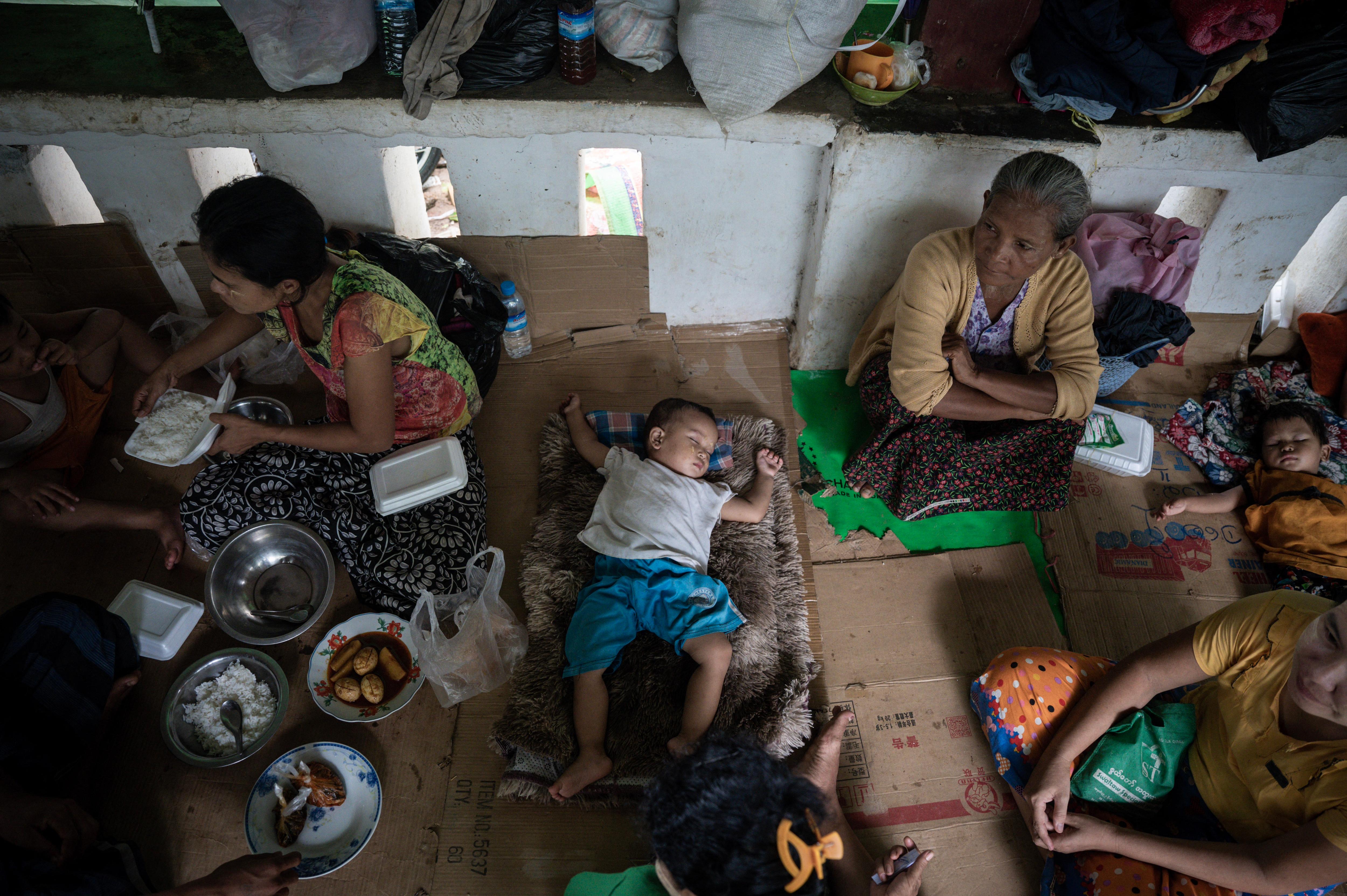 A baby sleeps on the floor as families eat nearby. 