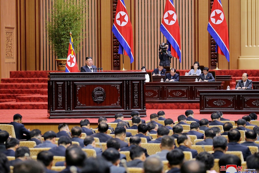 A gathering of parliamentarians look on as North Korean leader Kim Jong Un delivers a speech