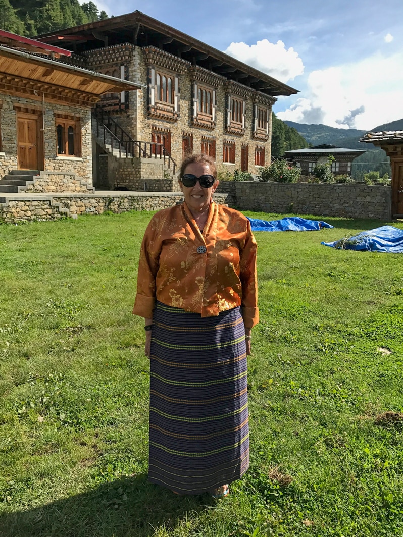 An Australian woman wearing Bhutanese clothes stands in front of a school in Bhutan.