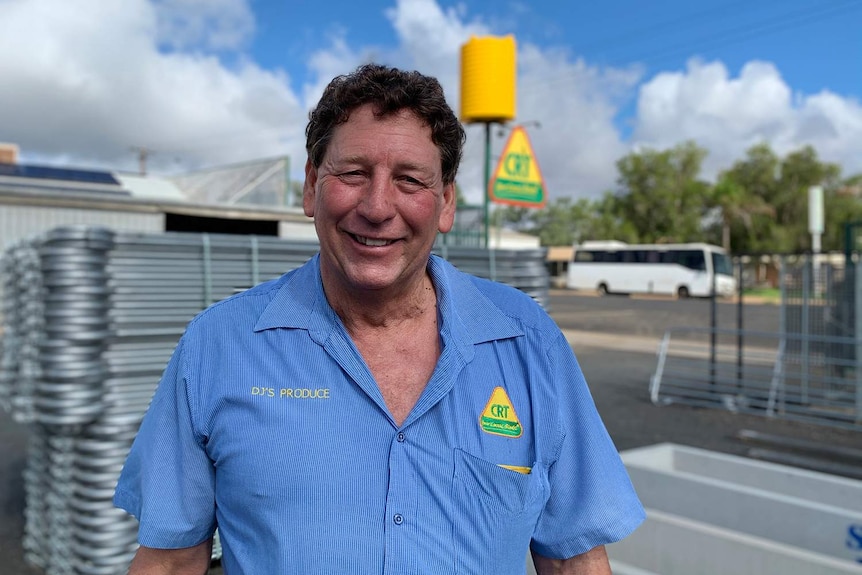 A man in a blue collared shirt smiles at the camera.