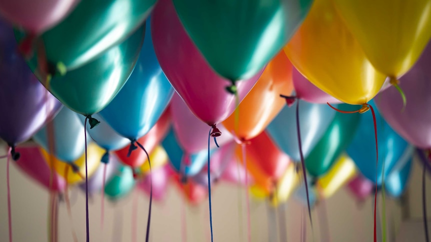 A photo of helium balloons at a birthday celebration.