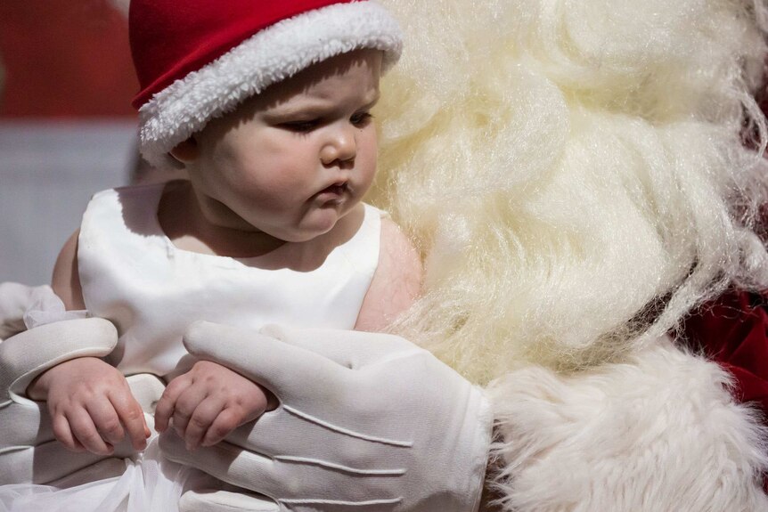 A baby is held in Santa's arms.