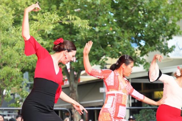 Three women perform cultural dances on stage.