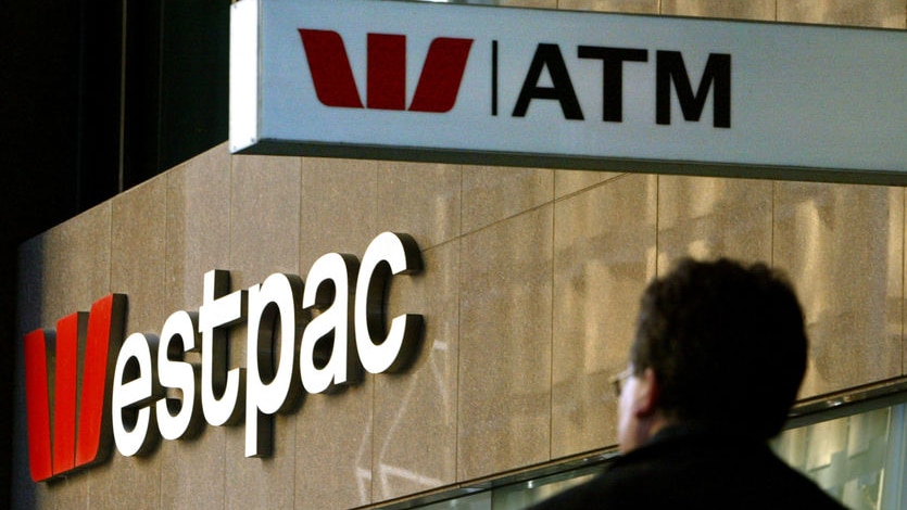 A pedestrian passes below a Westpac Bank sign in Sydney's CBD.