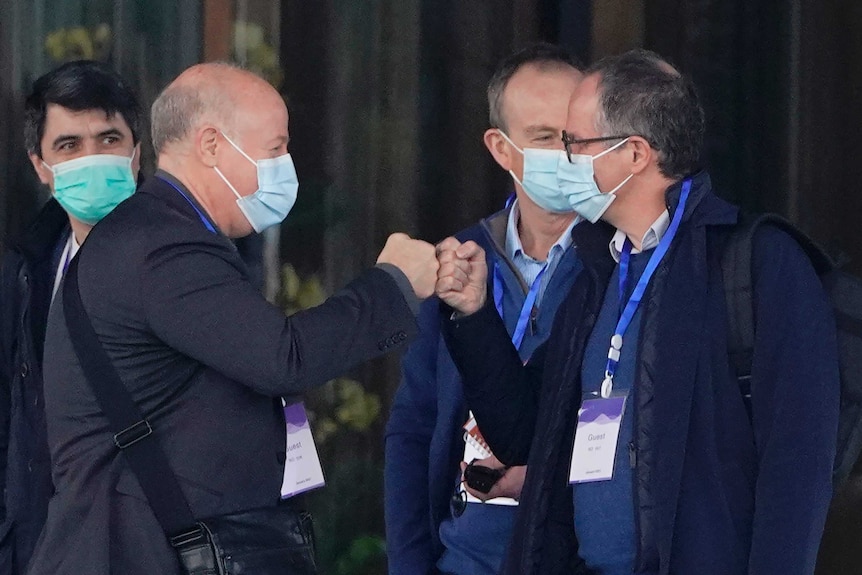 WHO-appointed expert Peter Daszak, left, bumps fists with colleague Peter Ben Embarek