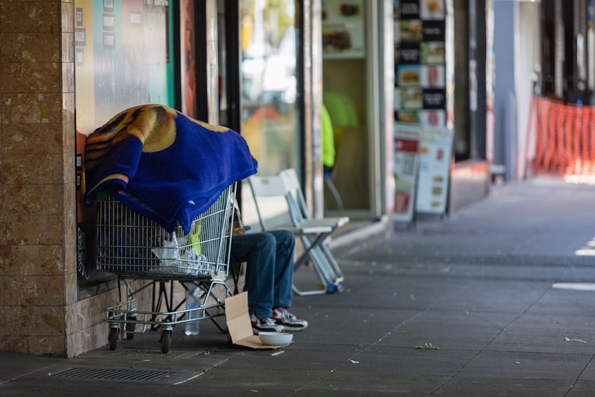 A person sits behind a trolley, collecting donations, in Fitzroy Street St Kilda, November 19, 2018.
