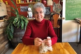 lady sitting at a table in a cafe knitting a scarf made from tea bag strings