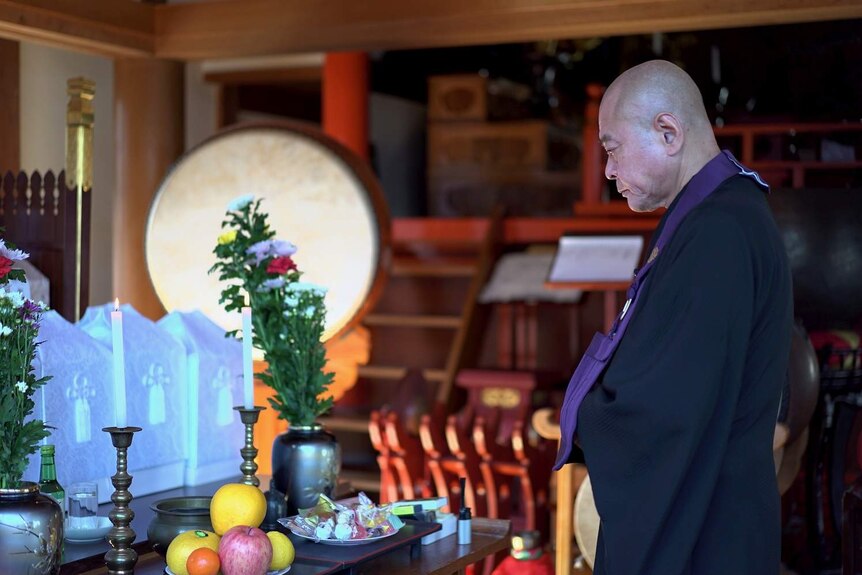 Buddhist monk prays in a temple in Japan.