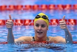 An Australian swimmer puts her two thumbs up in the pool after a gold medal swim at the world titles.