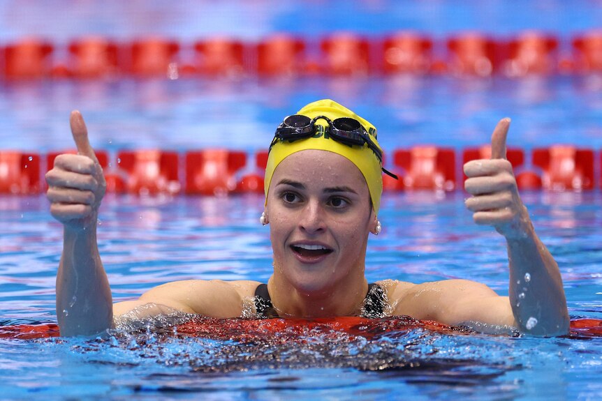 An Australian swimmer puts her two thumbs up in the pool after a gold medal swim at the world titles.