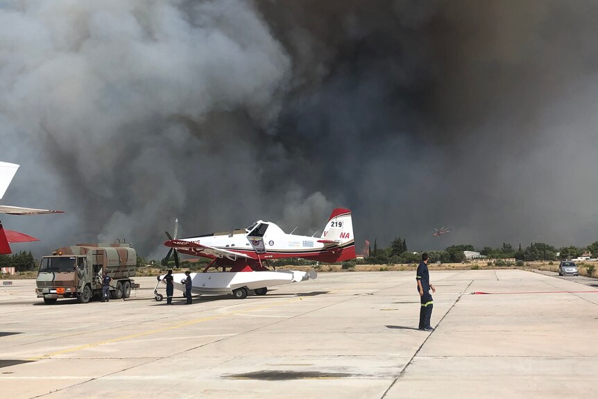 An amphibious aircraft on the tarmac at an airport with a huge cloud of smoke behind it.