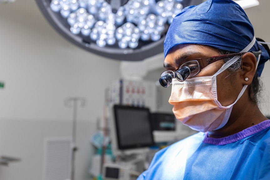 A male doctor wearing mask, hair covering and special surgery glasses