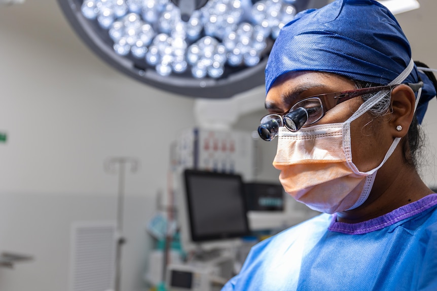 A male doctor wearing mask, hair covering and special surgery glasses