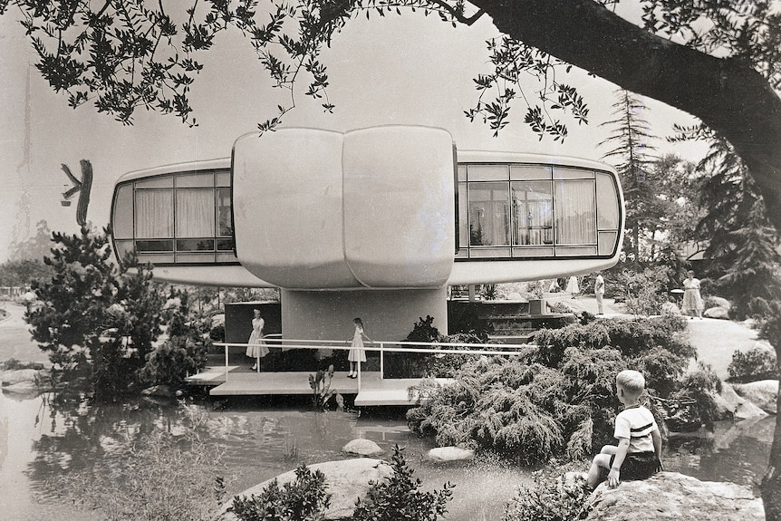 A black and white photo of a futuristic looking house with large windows by a lake