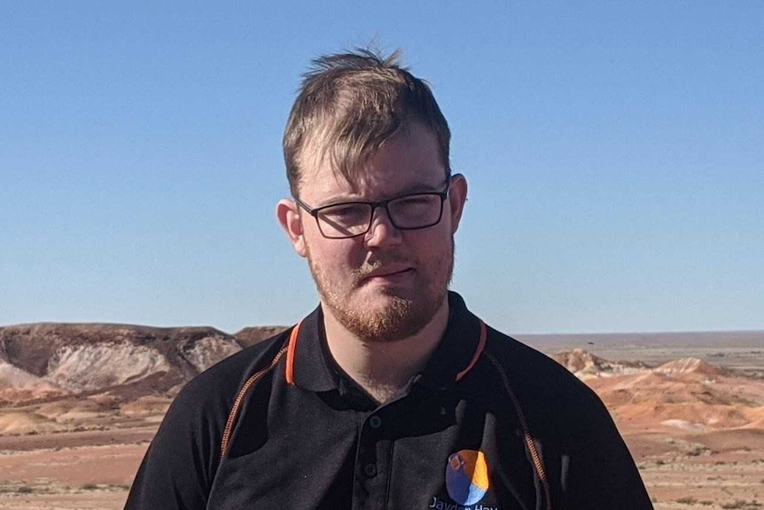 A man stands in front of a desert landscape.