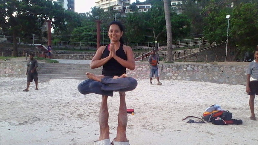 Fazilah Bazari holds a yoga pose, perched atop the legs of a yoga partner