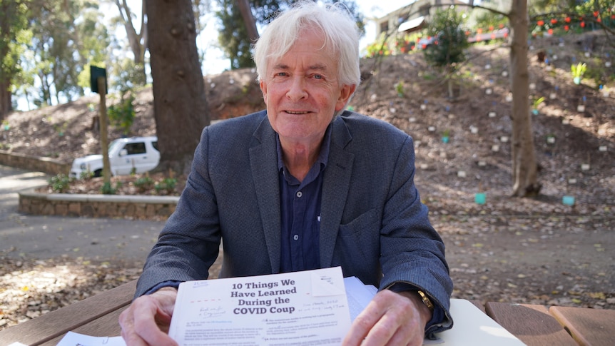 A man sitting at a picnic bench holding a piece of paper