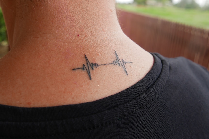 A close up of a neck with a heart echocardiogram tattoo