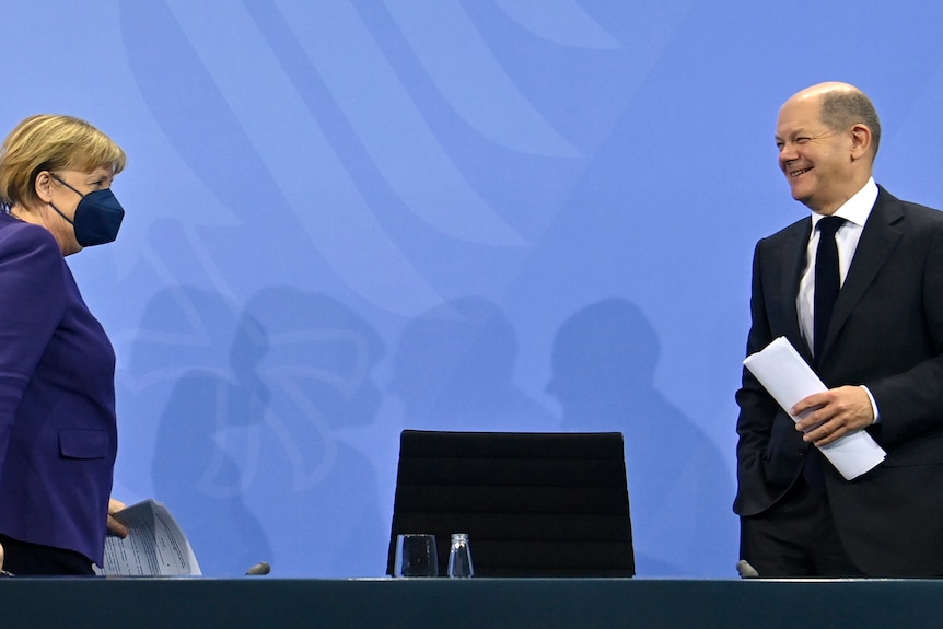 A woman and a man stand and smile at each other