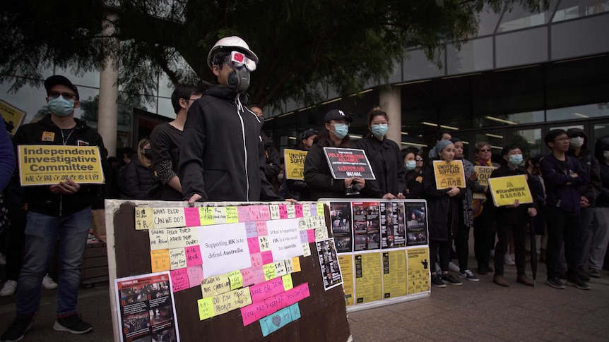 Protesters hold up signs while wearing masks at a rally in Adelaide