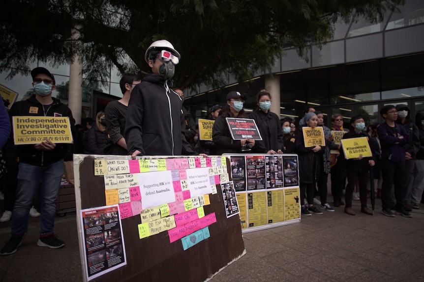 Protesters hold up signs while wearing masks at a rally in Adelaide