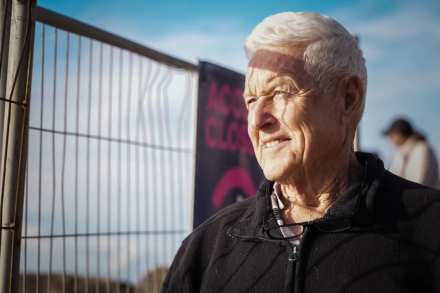 A man with grey hair looks out to sea