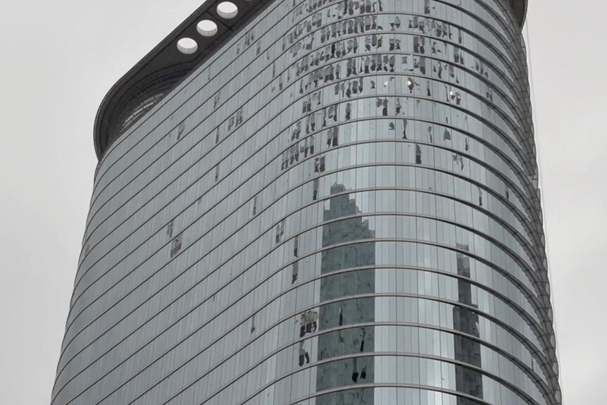 A large high-rise building wiht shattered windows. 
