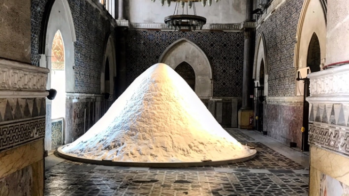 A huge pile of salt lies on the floor of an old, Mediterranean building.