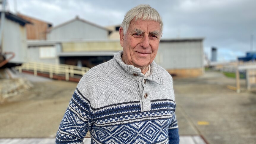 Man standing in front of old whaling station wearing knitted blue jumper