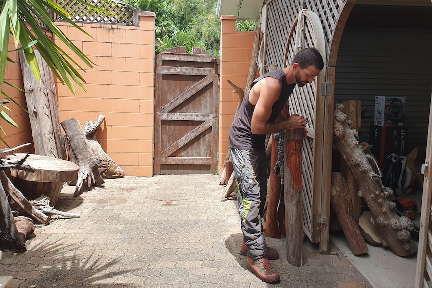 Man moving logs around in his courtyard