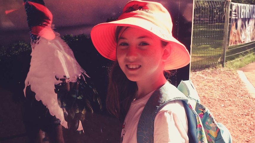 A girl with hat and backpack on a sunny day.
