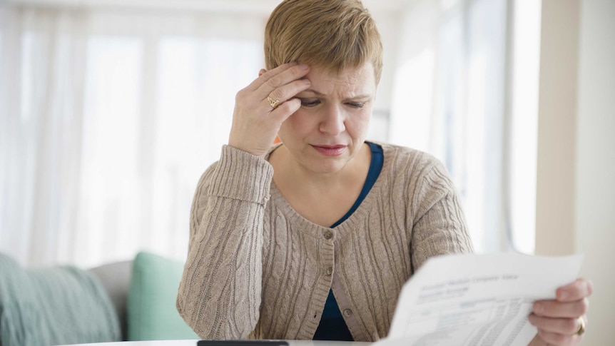 A woman gives a bill a worried look