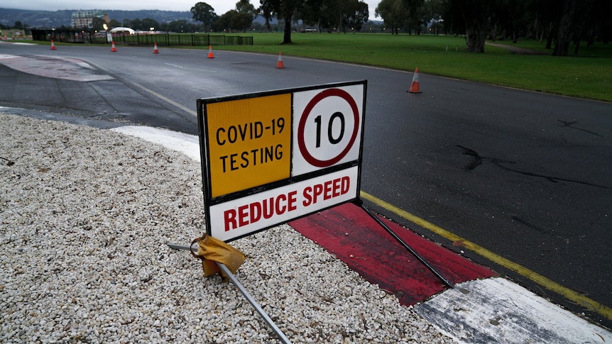 A sign that says COVID-19 testing, reduce speed