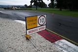 A sign that says COVID-19 testing, reduce speed
