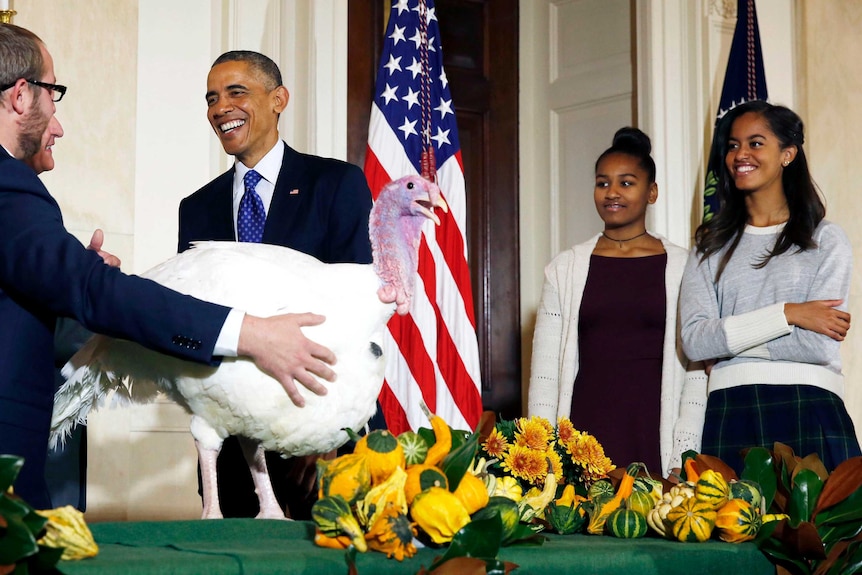 Barack Obama and his daughters participate in the annual turkey pardoning ceremony.