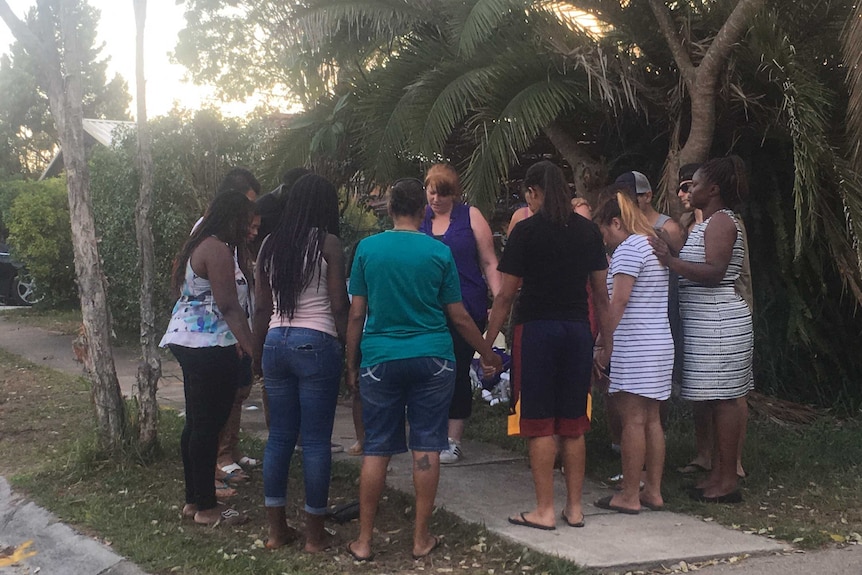 Mourners join hands outside the family home.