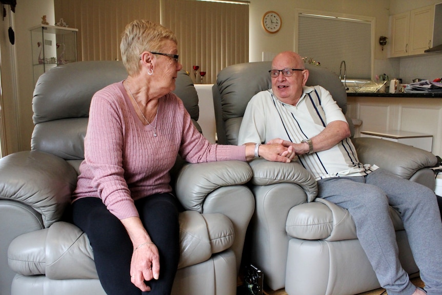 A photo of two older people holding hands lovingly while seated