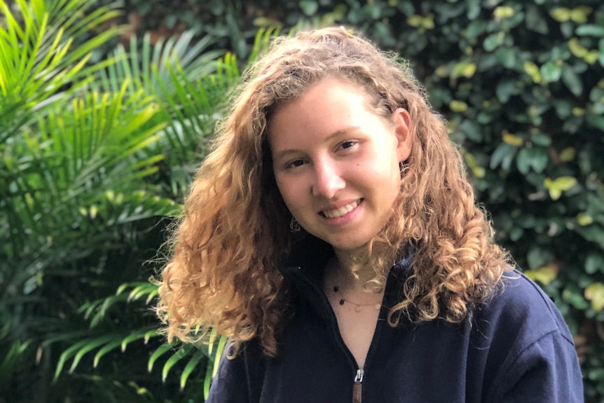 A young woman with curly hair smiling