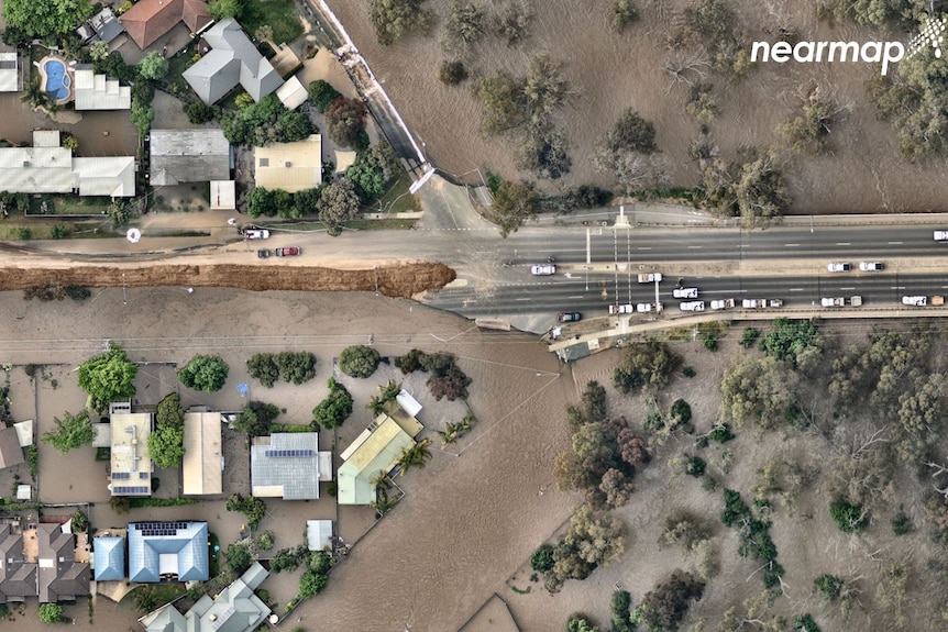 An aerial shot of floodwater s homes and ripping a road apart after river burst its banks.