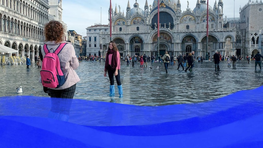 Tourists pose for photographs in St. Mark’s Square after days of severe flooding in Venice.