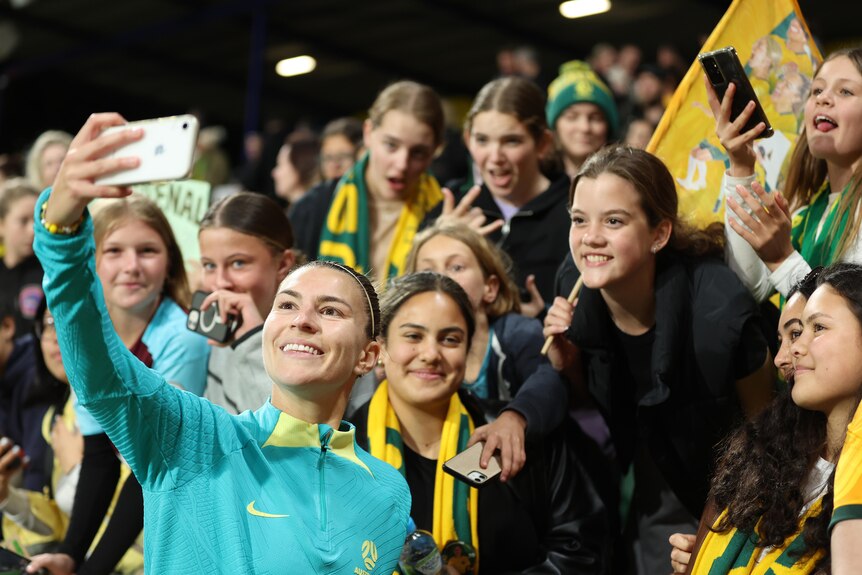 Steph Catley takes a selfie with fans in the crowd after a Matildas' Olympic Games qualifying match against Iran.