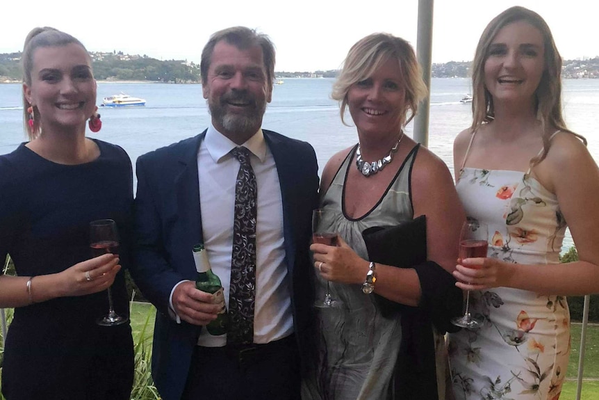 Keely Johnson, far right, stands with her sister, far left, with her dad centre-left and his partner centre-right.