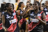 Tiwi Bombers women celebrate and join hands on the field.