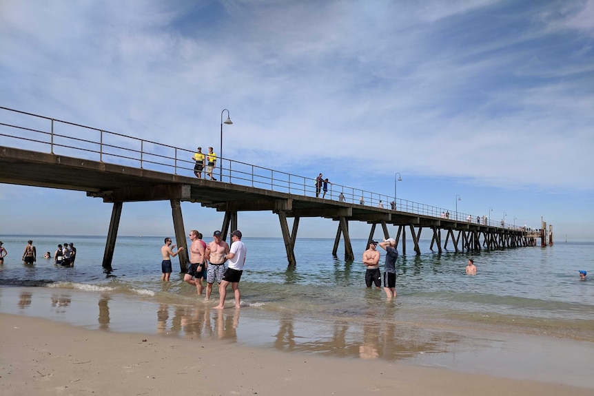 Beachgoers standing in front of Glenelg jetty